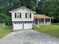 Charming split-level home featuring a two-car garage, front porch, and a well-maintained lawn at 6536 Rebecca Lou Ln, Lithonia, GA 30058