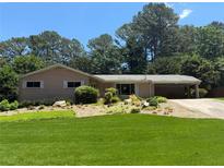 Charming single-story home featuring a lush lawn and mature trees, a driveway and a covered carport at 1533 High Haven Ne Ct, Atlanta, GA 30329