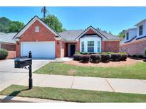 Charming single-story red brick home with a well-manicured lawn and attached two car garage at 2010 Hickory Station Cir, Snellville, GA 30078