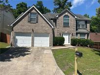 Charming brick home featuring a two-car garage, landscaped yard, and classic architectural details at 3827 Micah Ln, Ellenwood, GA 30294