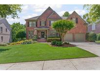 Beautiful two-story brick home with manicured lawn and attached two-car garage at 7047 Bennington Ln, Cumming, GA 30041