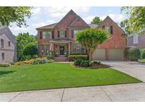 Charming two-story brick home with a well-manicured lawn and lush landscaping, offering great curb appeal at 7047 Bennington Ln, Cumming, GA 30041
