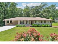 Charming single-story home featuring a covered carport, manicured lawn, and blooming flower beds at 3248 Wildwood Sw Dr, Marietta, GA 30060