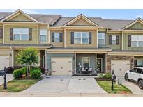 Charming townhome featuring a one-car garage, manicured lawn, and a cozy front porch, perfect for relaxing at 881 Ash St, Canton, GA 30114
