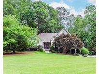 Landscaped home exterior boasting a well-manicured lawn, mature trees, and a charming front entrance at 1205 Rivershyre Ne Pkwy, Lawrenceville, GA 30043