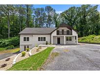 Charming two-story white home with a balcony, lovely landscaping, and a spacious driveway surrounded by mature trees at 1887 Shalimar Dr, Atlanta, GA 30345