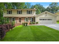 Charming two-story home with a manicured lawn, brick accents, and attached two-car garage at 3802 Sw Knights Bridge Sw Rd, Lilburn, GA 30047