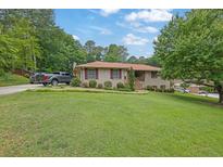 Ranch-style brick house with well-manicured lawn, trimmed bushes, and an adjacent pickup truck on driveway at 2149 New London Place Pl, Snellville, GA 30078