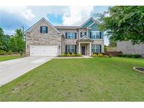 Charming two-story home with a manicured front lawn and a two car garage at 5789 Creek Indian Dr, Sugar Hill, GA 30518