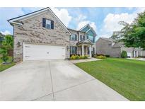 Charming brick home featuring a two-car garage and a well-manicured front lawn at 5789 Creek Indian Dr, Sugar Hill, GA 30518