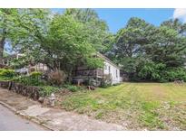 Quaint white home with a welcoming front porch, surrounded by mature trees and a green lawn at 1052 Curran Nw St, Atlanta, GA 30318