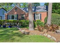 Charming brick home featuring a well-manicured front yard with mature trees and lush landscaping at 1521 Deerwood Dr, Decatur, GA 30030
