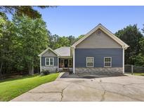 Charming home boasts a well-manicured lawn, blue siding, stone accents, and a long driveway leading to the residence at 735 Poplar Rd, Dallas, GA 30157