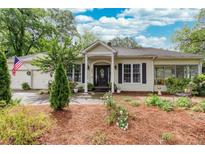 Charming single-story home with a welcoming front porch, lush landscaping, and an American flag at 791 E Main Street, Canton, GA 30114