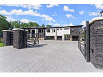 Modern home with black stone accents, white facade, and a large driveway with gated entrance at 1336 Azalea Dr, Lawrenceville, GA 30043