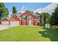 A beautiful two-story brick home with a well-manicured lawn and three car garage on a sunny day at 3524 Forest Downs Cv, Decatur, GA 30034