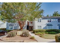 Light grey two-story condo featuring a well-manicured lawn and stairs leading to the upper level entrance at 72 Sutton Pl, Avondale Estates, GA 30002