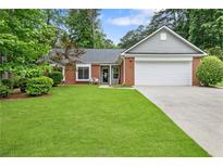 Beautifully landscaped front yard with a charming brick home and a two-car garage at 1208 Brandl Sw Dr, Marietta, GA 30008