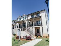 Charming white brick townhome featuring multiple levels, inviting staircases, and manicured landscaping at 3564 Shore Wood Ave, Lawrenceville, GA 30044
