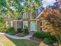 Charming brick home with a manicured front yard, beautiful landscaping and a light blue front door at 4295 Cami Way, Buford, GA 30519