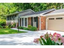 Charming home featuring a brick facade, well-manicured lawn, and beautiful landscaping at 6505 Whispering Ln, Atlanta, GA 30328