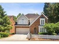 Charming two-story brick home with a manicured lawn, white picket fence and attached two-car garage at 2567 Briers North Dr, Dunwoody, GA 30360