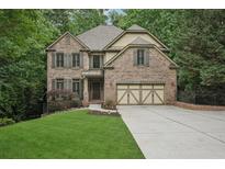 Beautiful brick home featuring a two-car garage, manicured lawn, and mature trees at 1917 Oak Grove Ne Rd, Atlanta, GA 30345