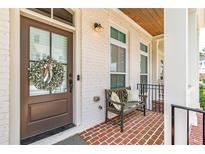 Charming front porch with brick floor, bench seating, and decorative wreath at 1964 Attell Way, Decatur, GA 30033