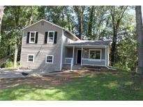 Charming two-story home with a covered porch and neutral siding surrounded by lush trees at 5561 Petite Pt, Lithonia, GA 30058