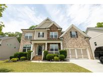 Charming two-story brick home with a welcoming front porch and well-manicured landscaping on a sunny day at 3589 Tamerton Trce, Buford, GA 30519