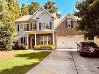 Charming two-story home featuring a mix of brick and siding, complemented by a well-manicured lawn and a two-car garage at 121 Royal Sunset Dr, Dallas, GA 30157