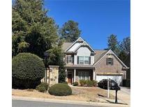 Charming two-story home featuring a manicured lawn, mature trees, and a brick and siding facade on a sunny day at 121 Royal Sunset Dr, Dallas, GA 30157