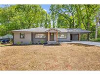 Charming gray home with a covered carport and newly landscaped front yard, set amongst mature trees at 1995 Mcafee Rd, Decatur, GA 30032