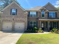 Charming two-story brick home featuring an attached two-car garage, covered porch and lush landscaping at 200 Birchwood Dr, Loganville, GA 30052