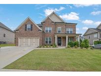 Charming brick home with a two-car garage and a well-manicured lawn and landscaped garden at 2740 Longacre Park Way, Lawrenceville, GA 30044