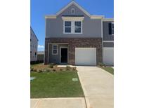 Charming two-story townhome featuring brick accents, a one-car garage, and freshly manicured landscaping at 312 Naples Way, Locust Grove, GA 30248