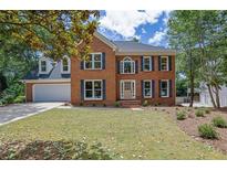 Charming two-story brick home with a well-manicured lawn, classic shutters, and an attached two-car garage at 4999 Willow Creek Dr, Woodstock, GA 30188