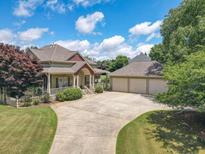 Inviting home with a spacious driveway and attached three-car garage, surrounded by lush greenery and trees at 105 Whippoorwill Way, Fayetteville, GA 30215
