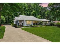 Beautiful single story home featuring a lush green lawn, mature trees and a long driveway at 290 Dania Dr, Alpharetta, GA 30009