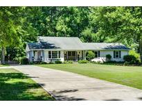 Charming one-story home with a long driveway and lush green lawn surrounded by mature trees at 290 Dania Dr, Alpharetta, GA 30009