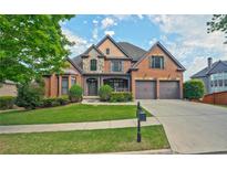 Stately two-story brick home featuring manicured landscaping, a two-car garage, and a welcoming front porch at 6477 Blue Water Dr, Buford, GA 30518