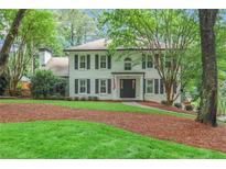 Charming white brick two-story home featuring black shutters, a well-manicured lawn, and mature trees at 3323 Lancing Ct, Duluth, GA 30096