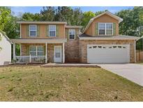 Charming two-story home with stone accents, green shutters, a cozy front porch, and a two-car garage at 1450 Steam Engine Way, Conyers, GA 30013