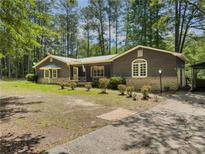 Charming one-story home with brown siding, lush lawn, and mature trees, offering a serene setting at 5216 Wheeler Dr, Loganville, GA 30052