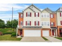 Attractive townhouse featuring a two-car garage, neutral siding, red shutters, and a well-maintained lawn at 5989 Turfway Park Ct, Sugar Hill, GA 30518