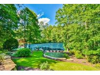 Secluded backyard featuring lush greenery, putting green, and lake views at 5675 Habersham Vly, Suwanee, GA 30024