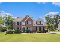Charming two-story brick home with lush lawn, manicured landscaping, and a symmetrical facade under a bright, blue sky at 1644 Beaver Creek Ln, Snellville, GA 30078