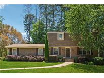Charming brick home featuring manicured lawn, mature trees, and inviting front entrance at 461 Village Green Sw Ct, Lilburn, GA 30047