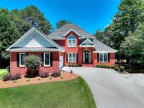 Charming brick home with well-manicured lawn, long driveway, and lush landscaping on a sunny day at 781 Templeton Dr, Loganville, GA 30052