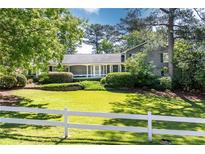 Charming gray home featuring a well-manicured front lawn, complemented by a classic white picket fence at 3099 Farmington Se Dr, Atlanta, GA 30339